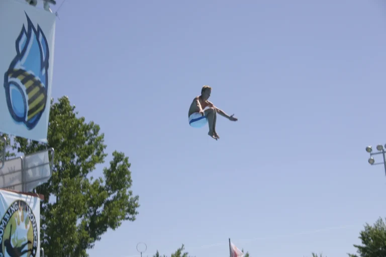 Ein Springer mit angewinkelten Beinen und geöffneten Armen neben dem Turm vor blauem Himmel, 2005.