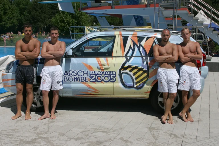 Vier Teammitglieder vor dem gebrandeten Arschbombe-Eurotour-2005-Fahrzeug am Freibad.
