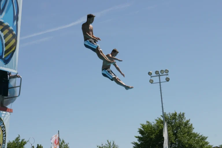 Zwei Springer gleichzeitig in der Luft neben dem Turm vor blauem Sommerhimmel, 2005.