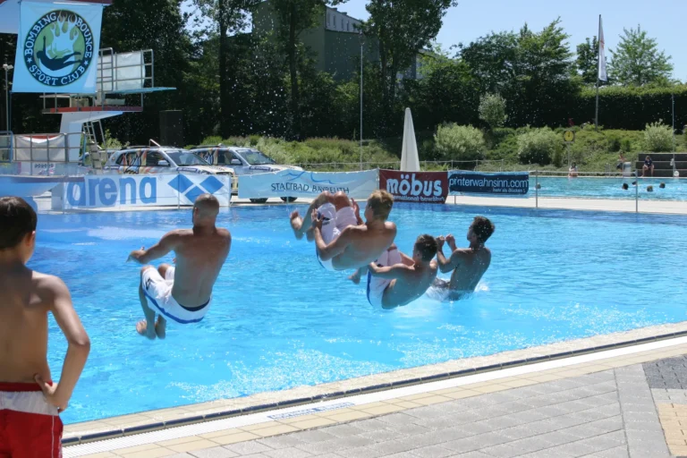 Mehrere Mitglieder der ersten Arschbomben-Nationalmannschaft springen gemeinsam ins Freibadbecken, 2005.
