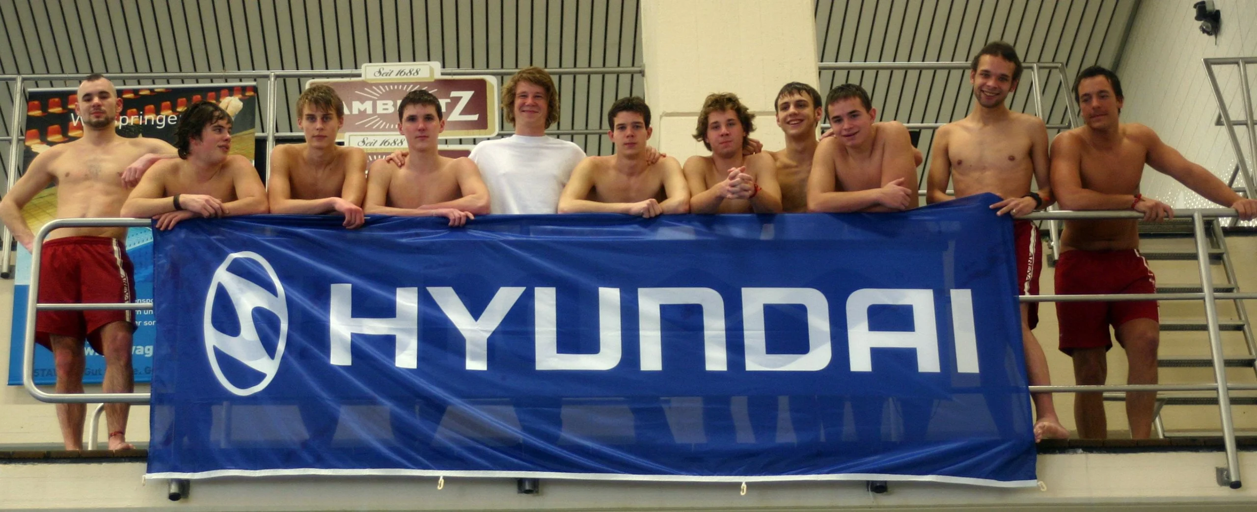 Arschbombe national team behind a large Hyundai banner inside an indoor pool, Kick Ass show 2005.