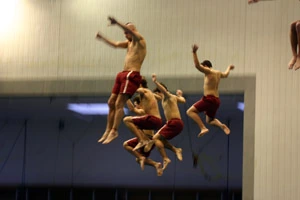 Several divers in red shorts airborne together in a group dive, 2005.