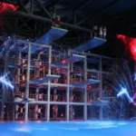 Showbühne mit Sprungturm, Fontänen und dem sichtbaren Titel „Die Pool Champions“. Eigene Archivaufnahme, Kameradatum 21. Juni 2013. Kein Foto der August-WM im Sommerbad Neukölln.